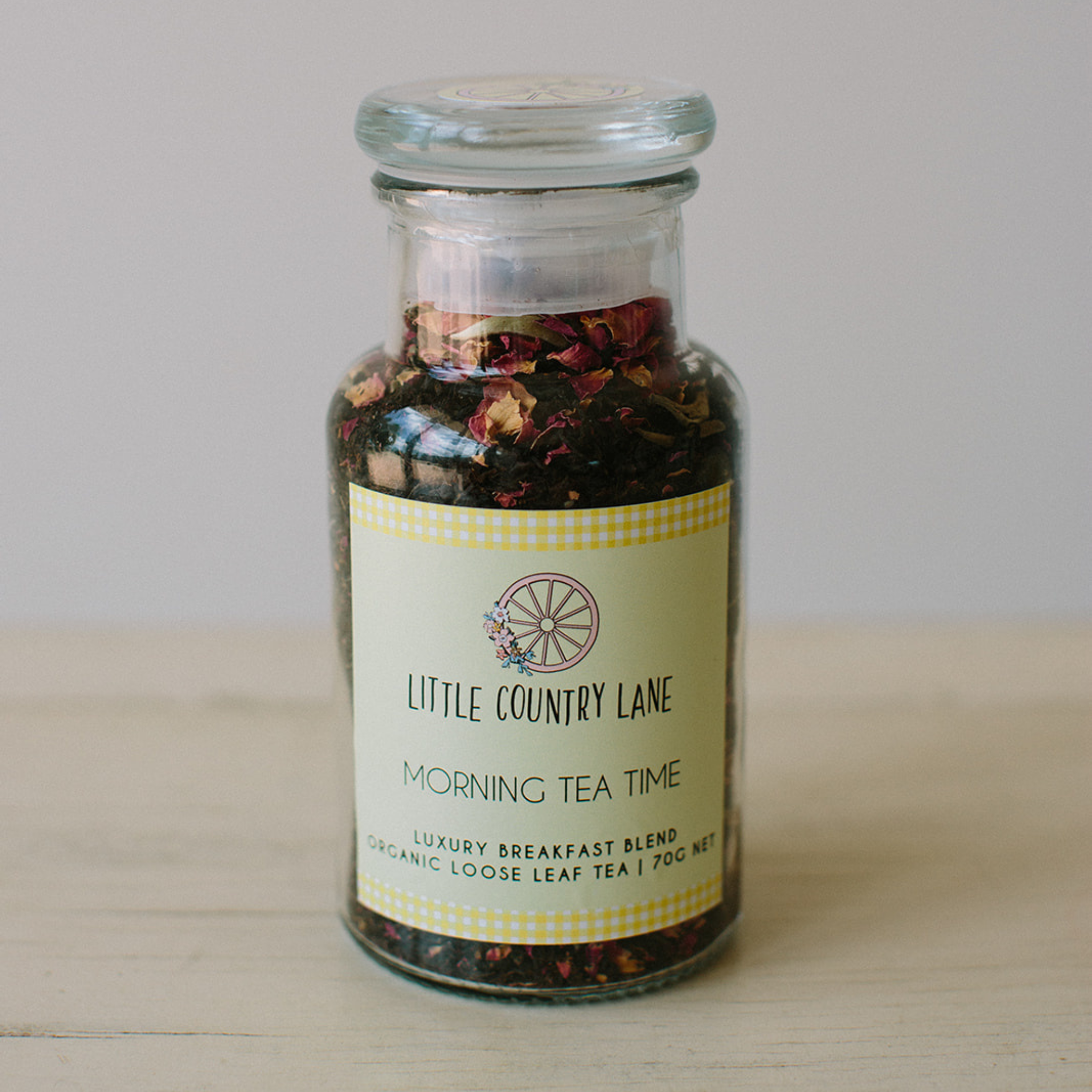 Glass jar of 'Morning Tea Time' tea blend from Little Country Lane on a wooden surface.